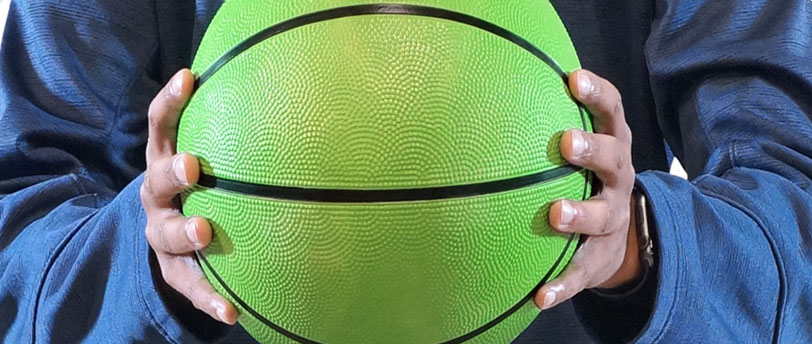 a man's hand holding a green basketball